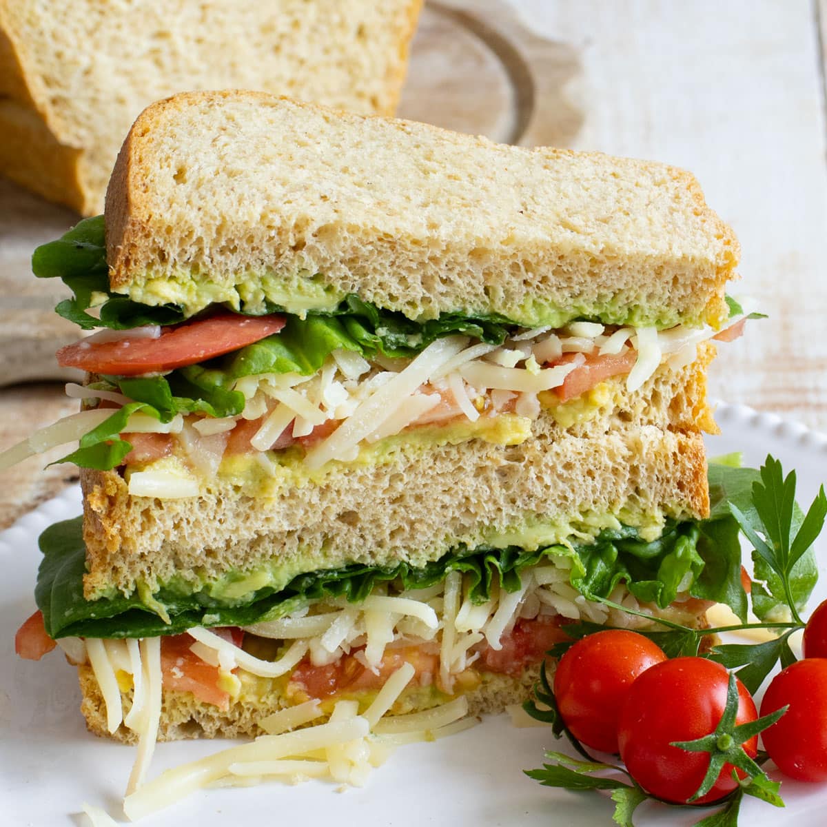 Keto sandwich sliced open filled with avocado, lettuce, tomato and cheese.
