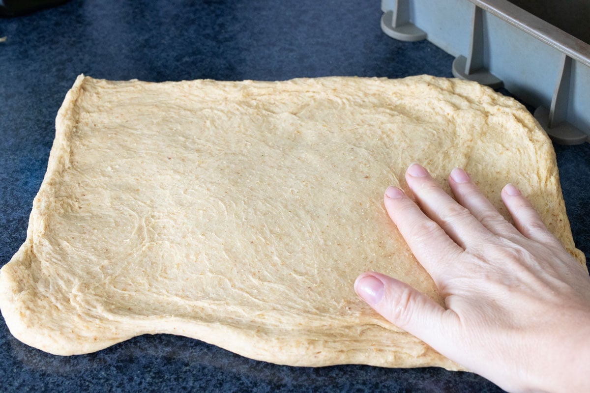Stretching the dough into a large rectangle.