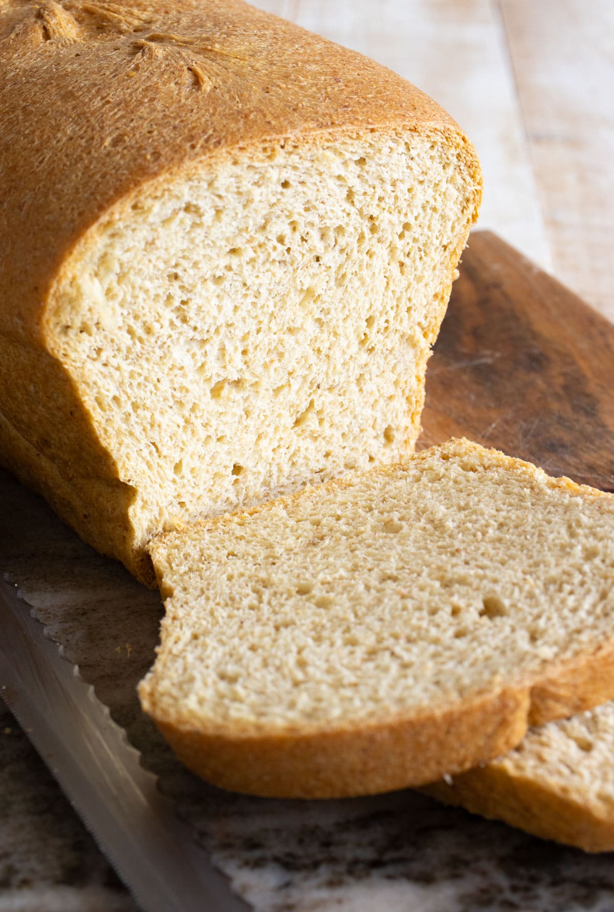 Keto yeast bread loaf sliced with a knife on the side.