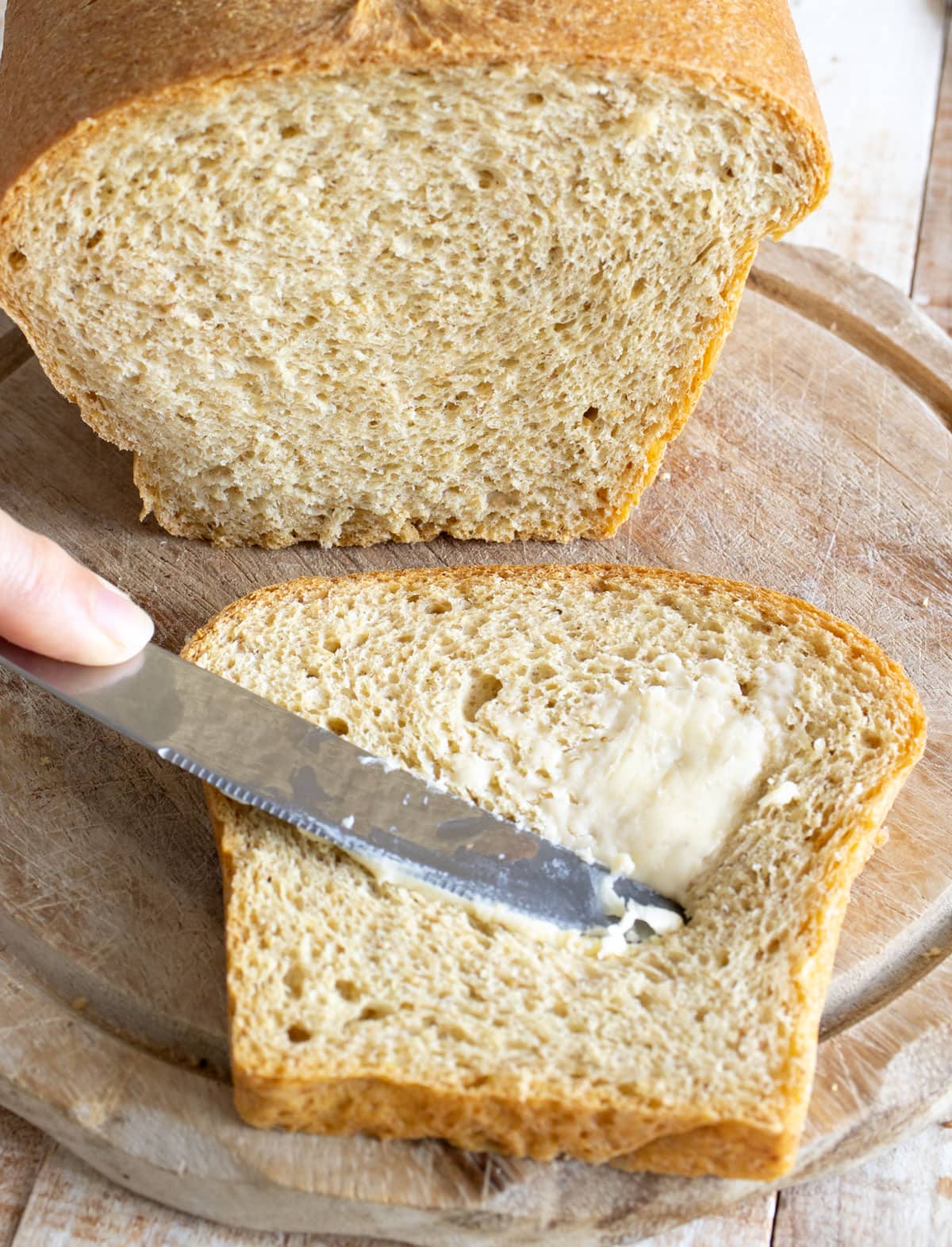 Spread ing a slice of keto sandwich bread with butter.