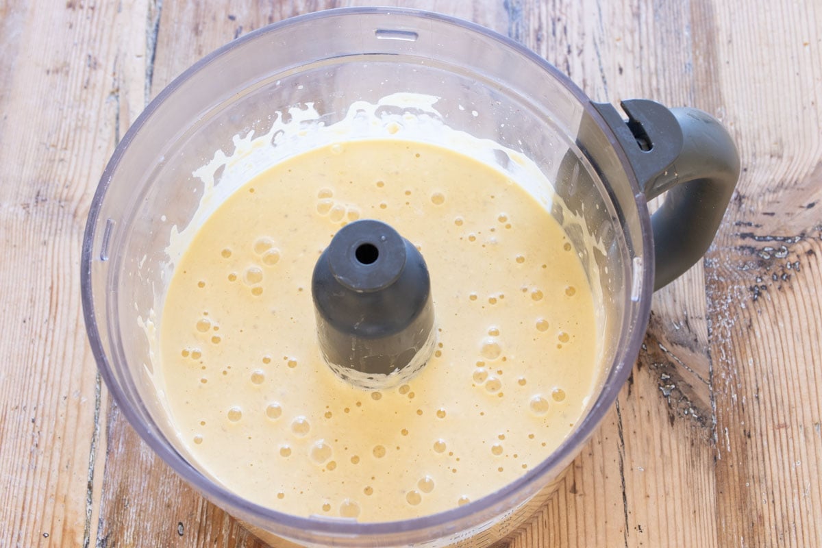 Whipped wet ingredients in a food processor bowl.