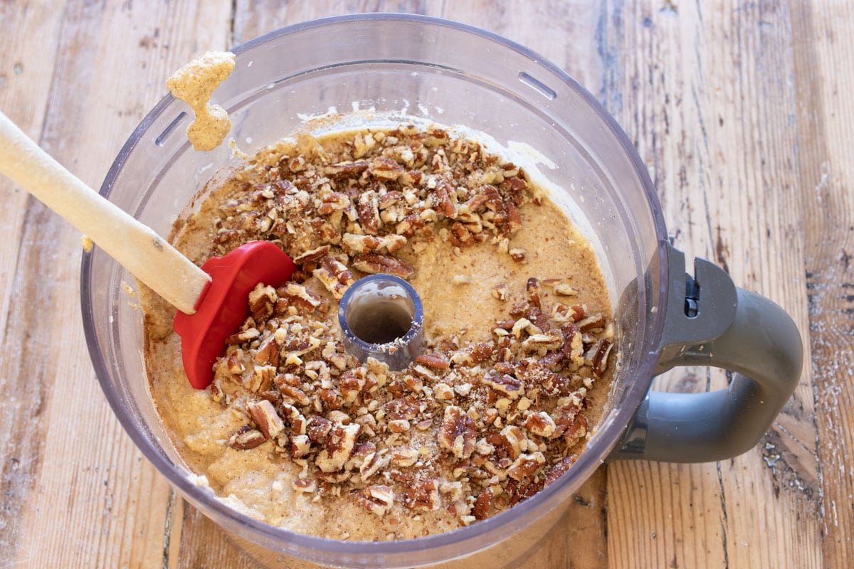 Stirring crushed pecans into the banana bread batter.