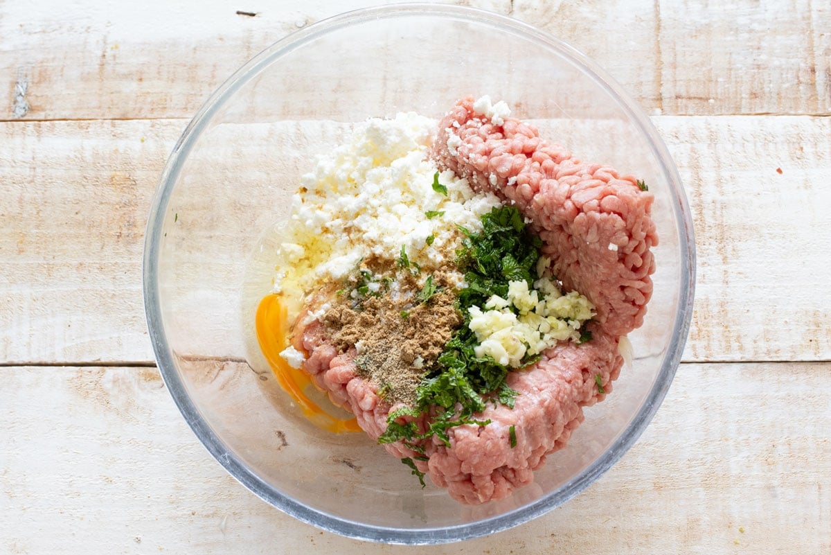 All ingredients to make lamb feta meatballs in the mixing bowl.