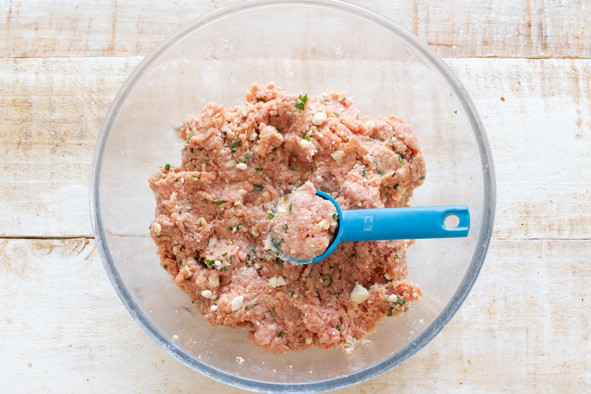 A bowl with the ground lamb mixture and a measuring tablespoon to portion the meatballs.