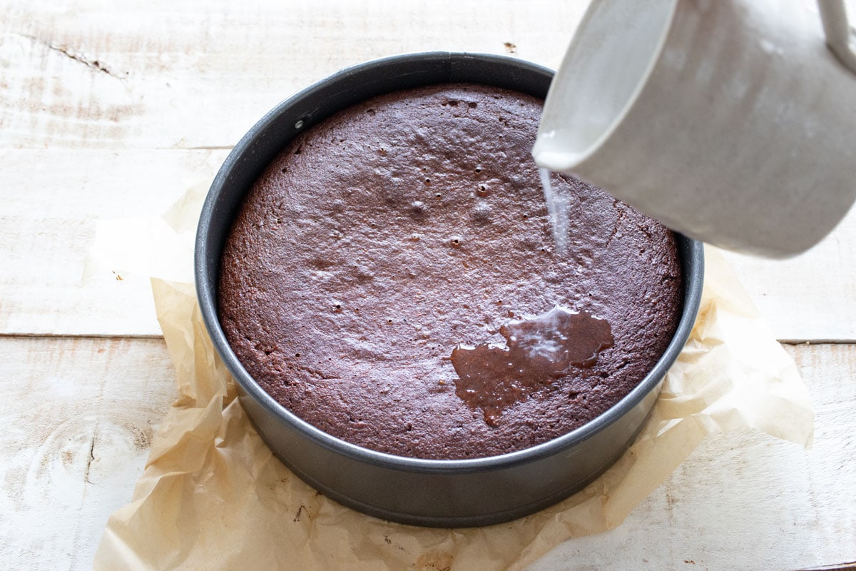Pouring the rose lemon drizzle syrup over the cake.
